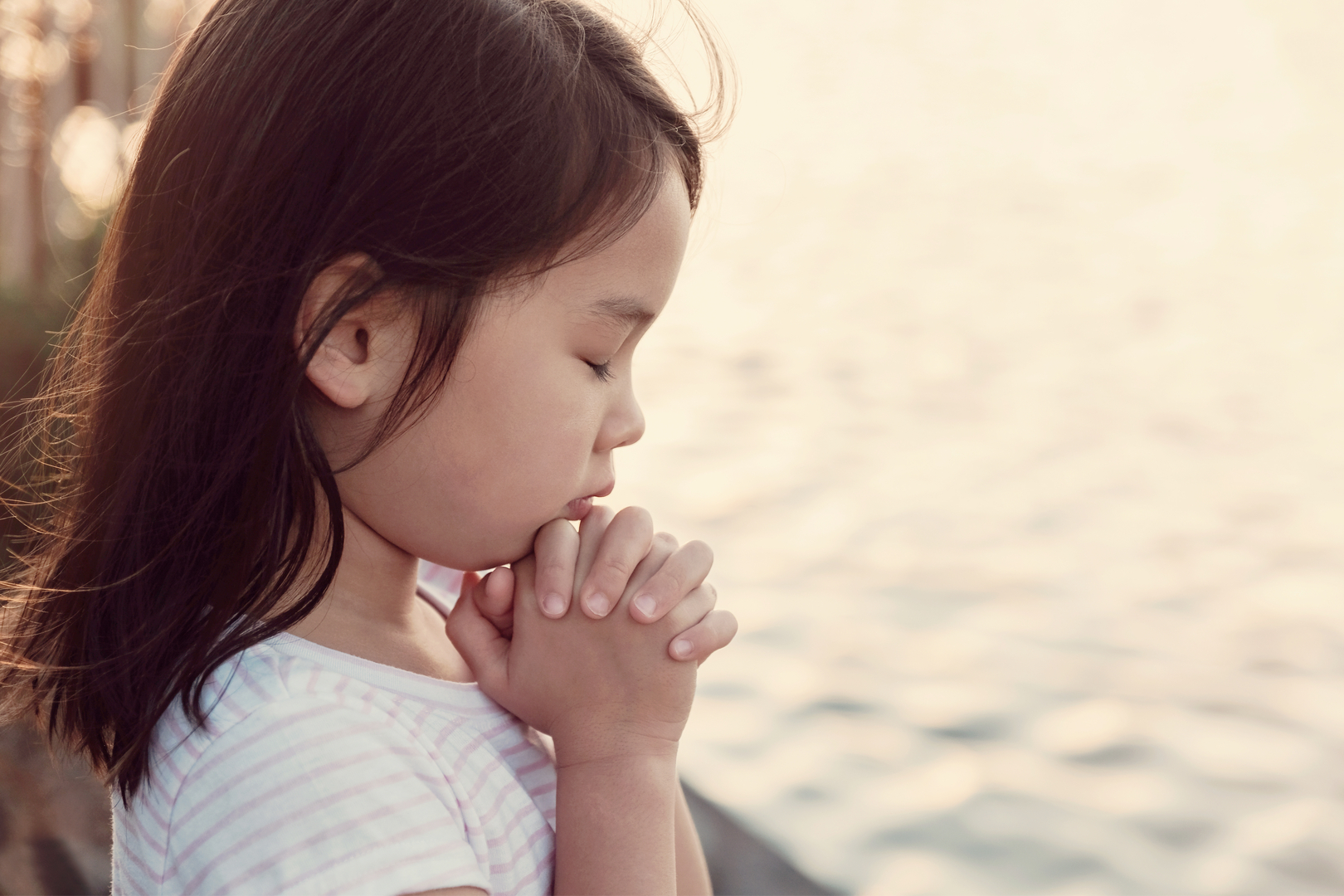 Little girl praying next to the waters